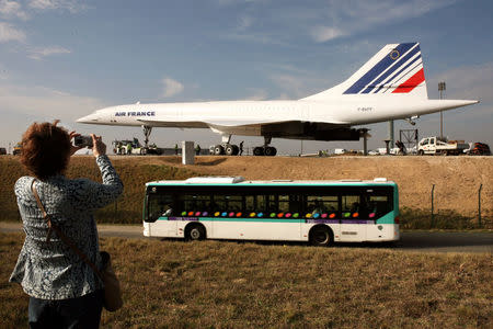 FILE PHOTO: A woman takes a photo of retired Air France Concorde number 5 as it is pulled from a hangar towards its final residence on the tarmac of Roissy airport, northern Paris, October 17, 2005. REUTER/Jacky Naegelen/File Photo