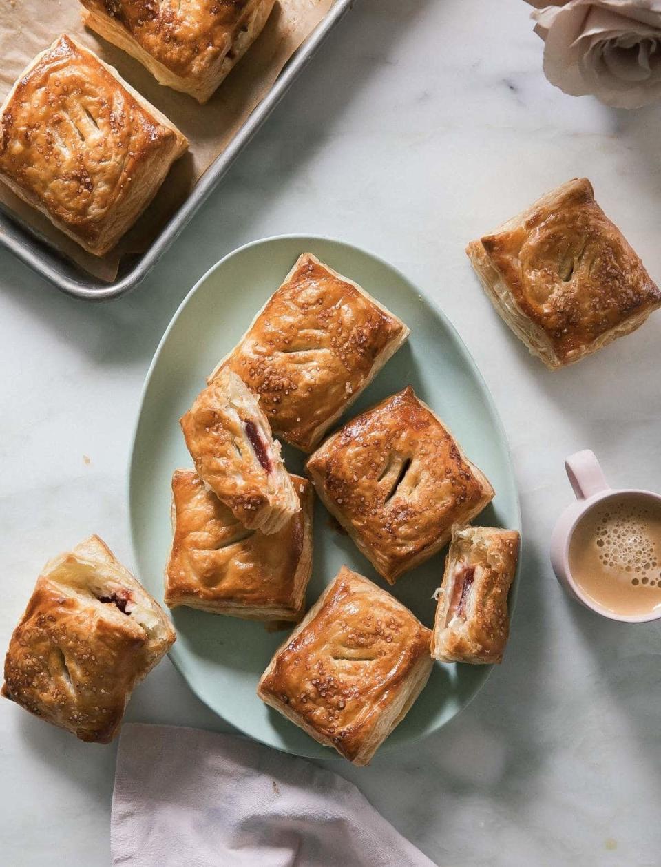 Assorted pastries on a plate beside a cup of coffee, some cut open to show filling