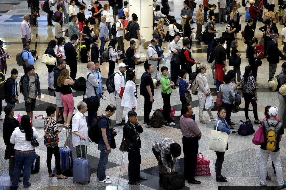 FILE - In this Sunday March 16, 2014 file photo, travelers queue at the immigration counters as they make their way through the departure hall at the Kuala Lumpur International Airport in Sepang, Malaysia. (AP Photo/Wong Maye-E, File)