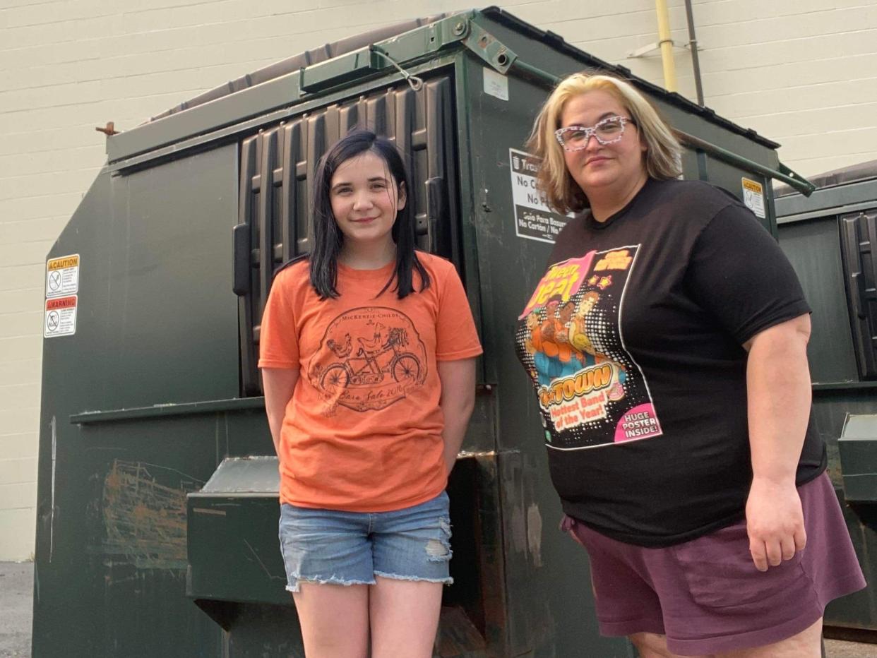 Mom and daughter in front of dumpster