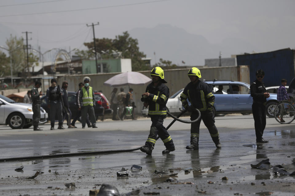 Afghan firefighters work at the site of a bomb explosion near a damaged vehicle in Kabul, Afghanistan, Monday, April 27, 2020. Kabul police said a sticky bomb attached to a vehicle detonated in the capital but caused no casualties. (AP Photo/Rahmat Gul)