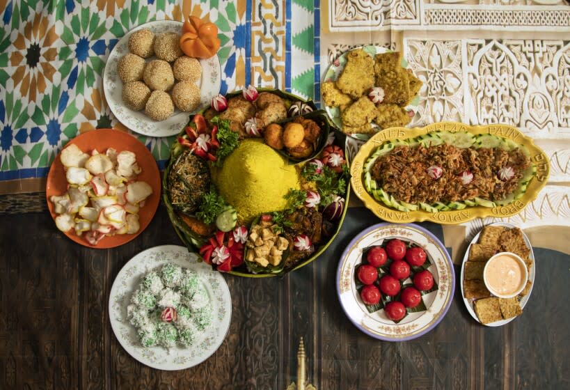 LOS ANGELES, CA - DECEMBER 19: The nasi kuning, centerpiece, is a dish made for special celebrations. Clockwise from upper right are: tempeh mendoan, bala bala sayuran, tempeh goreng, kue ku, klepon, krupuk and onde onde goreng. Photographed at Masjid At-Thohir on Sunday, Dec. 19, 2021. (Myung J. Chun / Los Angeles Times)