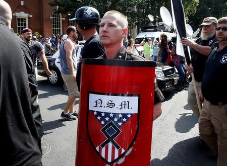 A white nationalist holds a shield with National Socialist Movement symbols on it as he arrives at a rally in Charlottesville, Virginia, U.S., August 12, 2017. REUTERS/Joshua Roberts/Files