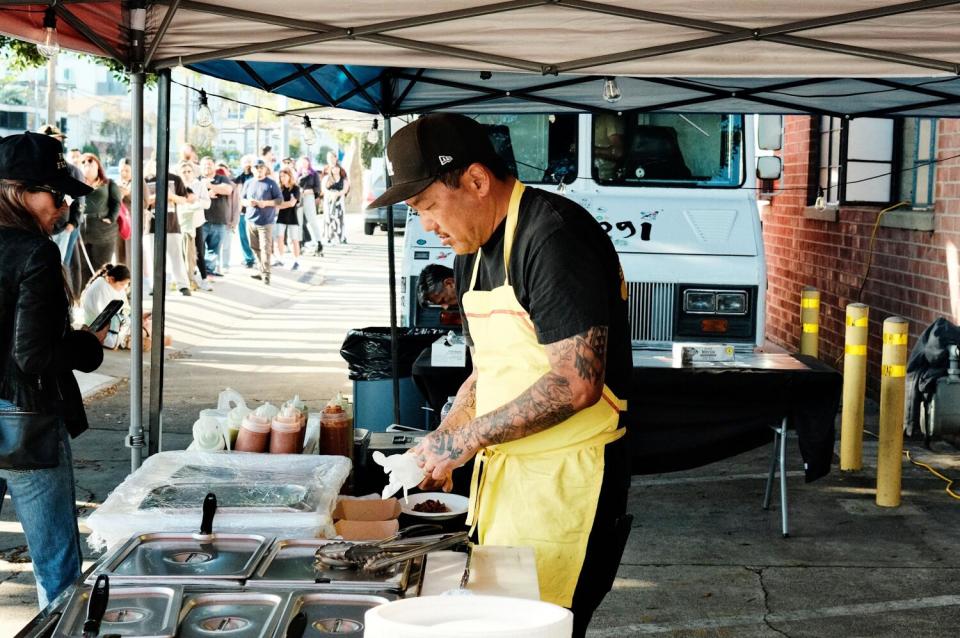 Chef Roy Choi prepares a taco at an outdoor taco stand.