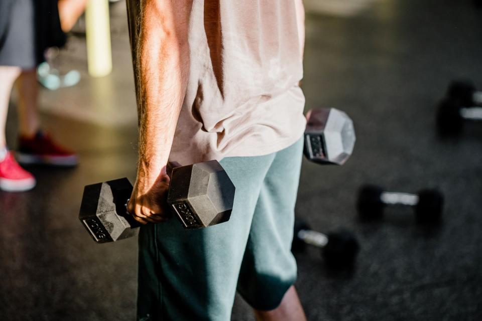 fit male exercising with dumbbells in gym