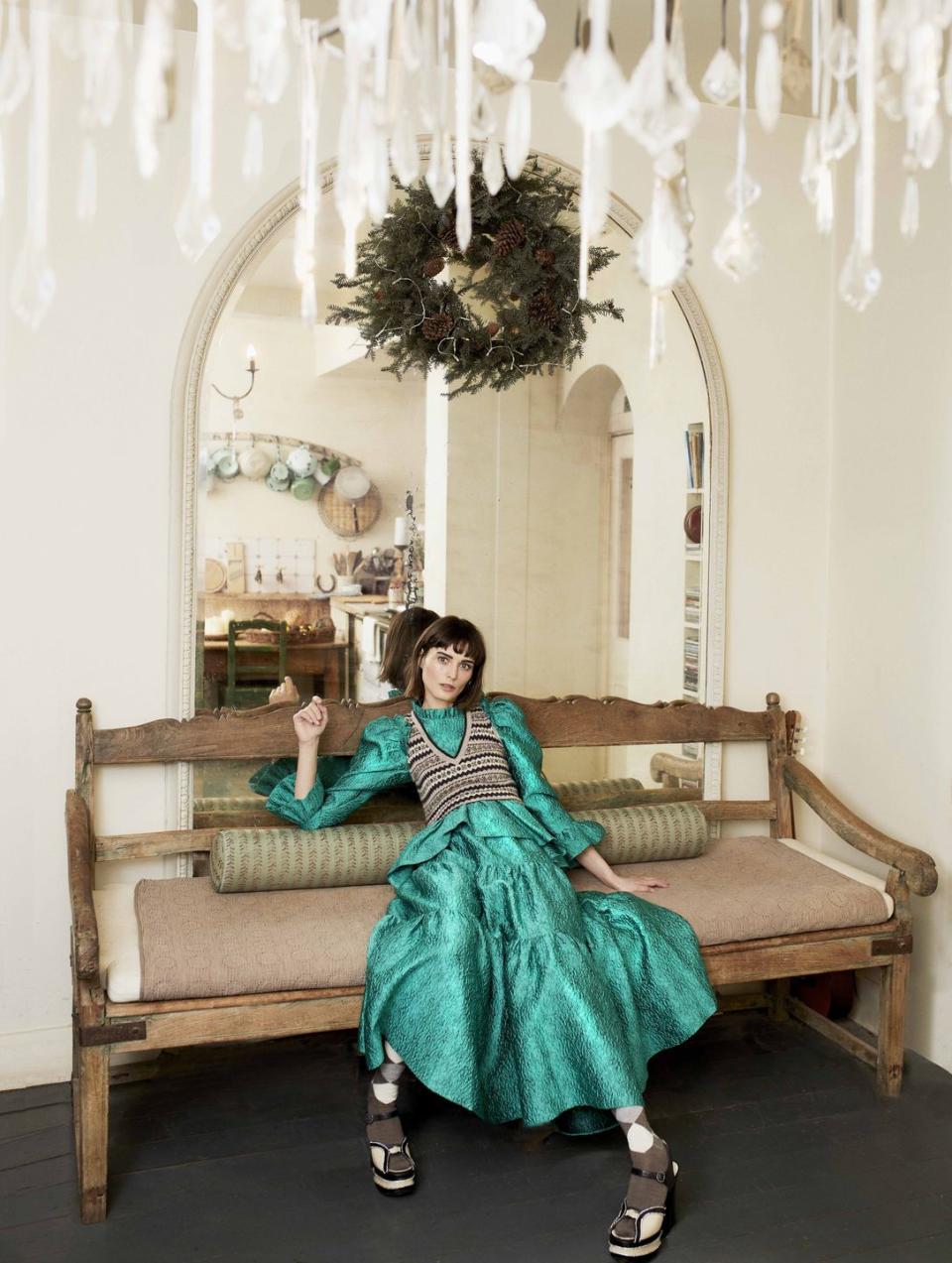 model shown slouching on couch in front of mirror, room decorated with wreath and chandelier wearing sweater vest, Â£295, brora top skirt, both Â£poa, ulla johnson socks, Â£19, burlington shoes, Â£645, philosophy di lorenzo serafini