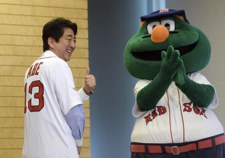 Japan's Prime Minister Shinzo Abe (L) smiles as he wears a jersey of the Boston Red Sox, while Red Sox mascot Wally (R) looks on at Abe's office in Tokyo January 21, 2014. REUTERS/Yoshikazu Tsuno/Pool