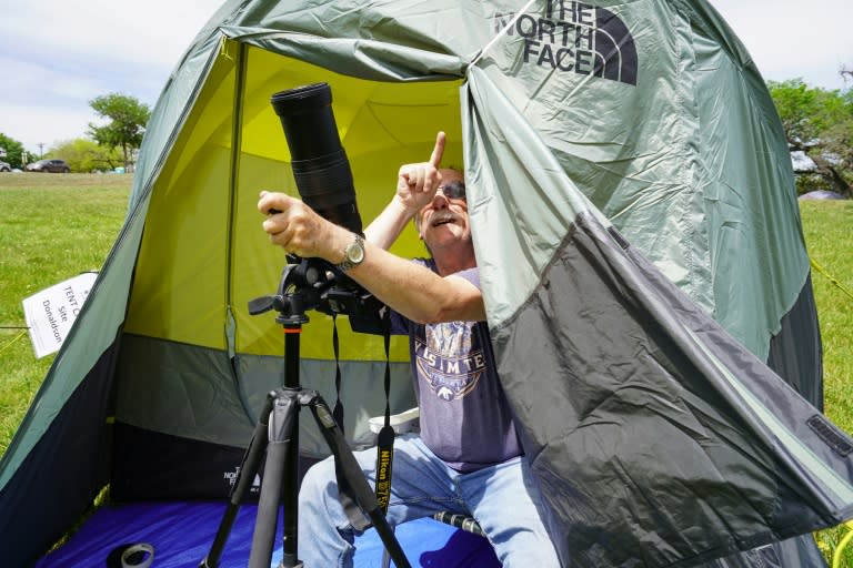 Un campeur installé sous une tente au parc Stonehenge II, prépare son équipement photographique la veille de l'éclipse solaire totale de lundi en Amérique du Nord, le 7 avril 2024 à Ingram, au Texas (Cécile Clocheret)