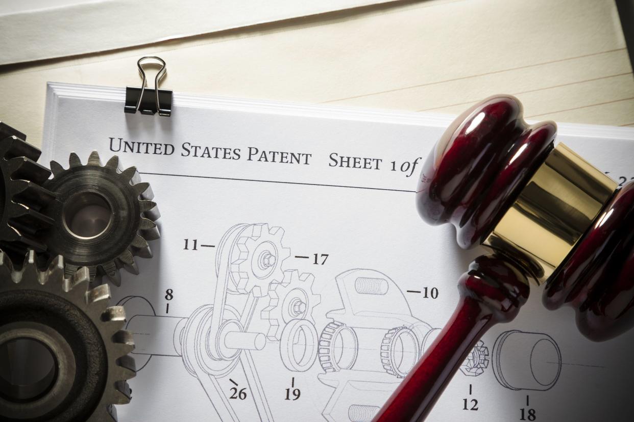 gavel next to gears and mechanical diagram for patent application