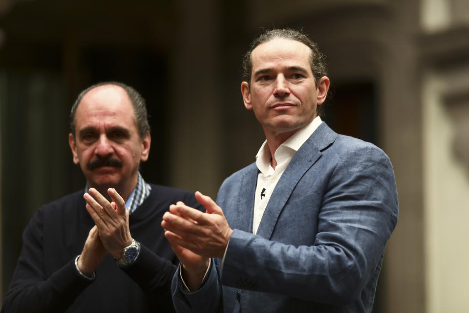 Federico Acosta, a Mexican who traces his lineage back 16 generations back to Moctezuma's daughter, left, and Italian Ascanio Pignatelli also of the 16th generation, descended from Hernan Cortes' daughter, applaud during a press conference in Mexico City, Friday, Nov. 8, 2019. Descendants of the Spanish conquistador and the Aztec emperor are meeting in Mexico City to mark the 500th anniversary of their forbearers' first encounter. The hope was that this meeting, at a colonial church where Cortes is buried, would go better than the one 500 years ago. (AP Photo/Eduardo Verdugo)