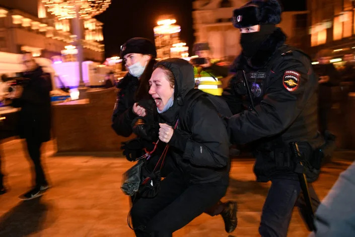 A woman screams as two police officers grab her from behind.