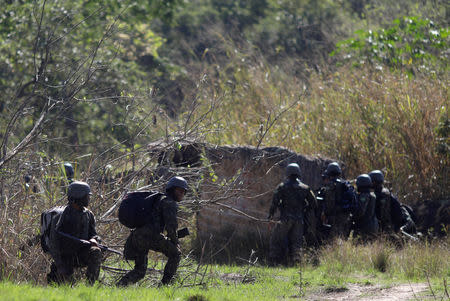 Brazilian Army soldiers take cover during a shootout with drug gangs during an operation in Alemao slums complex in Rio de Janeiro, Brazil August 20, 2018. REUTERS/Ricardo Moraes