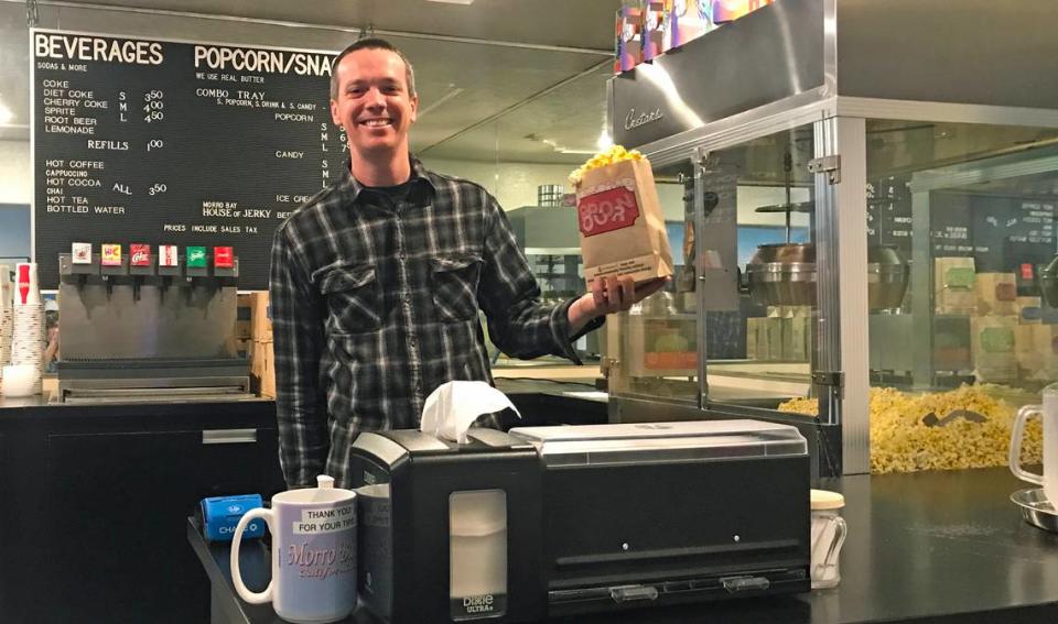 Cameron Wilson, new onsite manager of the Bay Theater in Morro Bay, holds a bag of fresh popcorn. His family just bought the 81-year-old business and building in October 2023.
