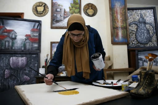 Wafaa al-Adhami, 46, a Palestinian artist and mother, paints at her home in the West Bank town of Hebron