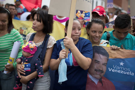 Josefina Guevara (C), 37, holds a campaign placard depicting Venezuela's President Nicolas Maduro and late President Hugo Chavez, next to her daughters Beatriz and Isabel, and her granddaughter Osmelis, during a campaign rally in Caracas, Venezuela May 16, 2018. Picture taken May 16, 2018. REUTERS/Carlos Garcia Rawlins