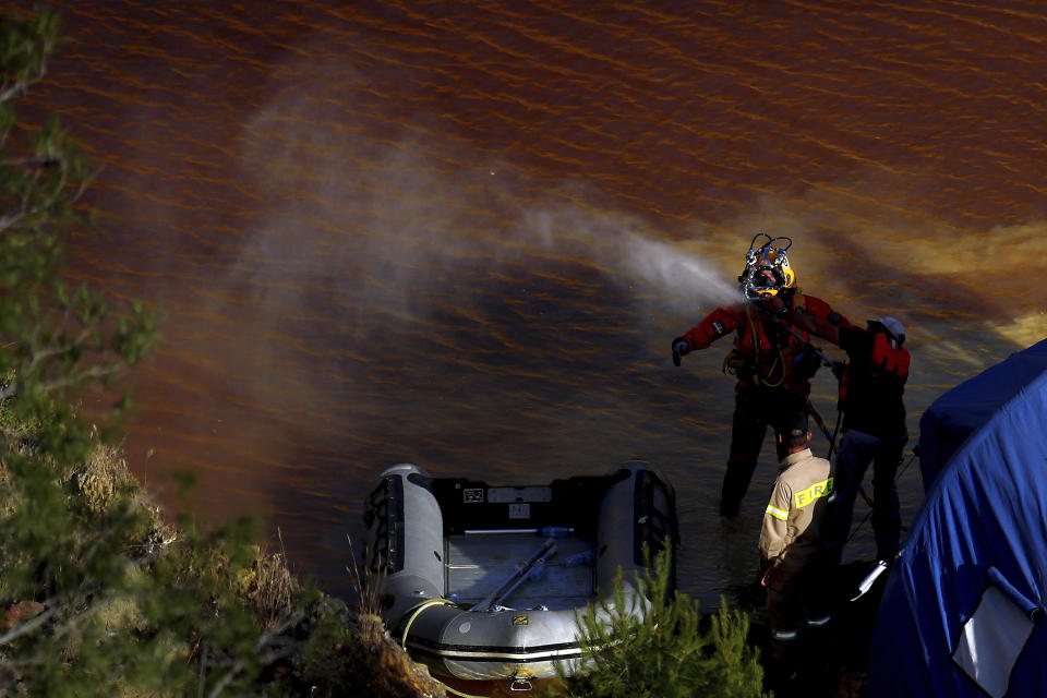 A man is sprayed clean with water after a dive in a toxic man-made lake during a search for a third suitcase near the village of Mitsero outside of the capital Nicosia, Cyprus, Tuesday, May 7, 2019. New police chief Kypros Michailides has apologized to the families of seven foreign women and girls who an army captain has confessed to killing. (AP Photo/Petros Karadjias)