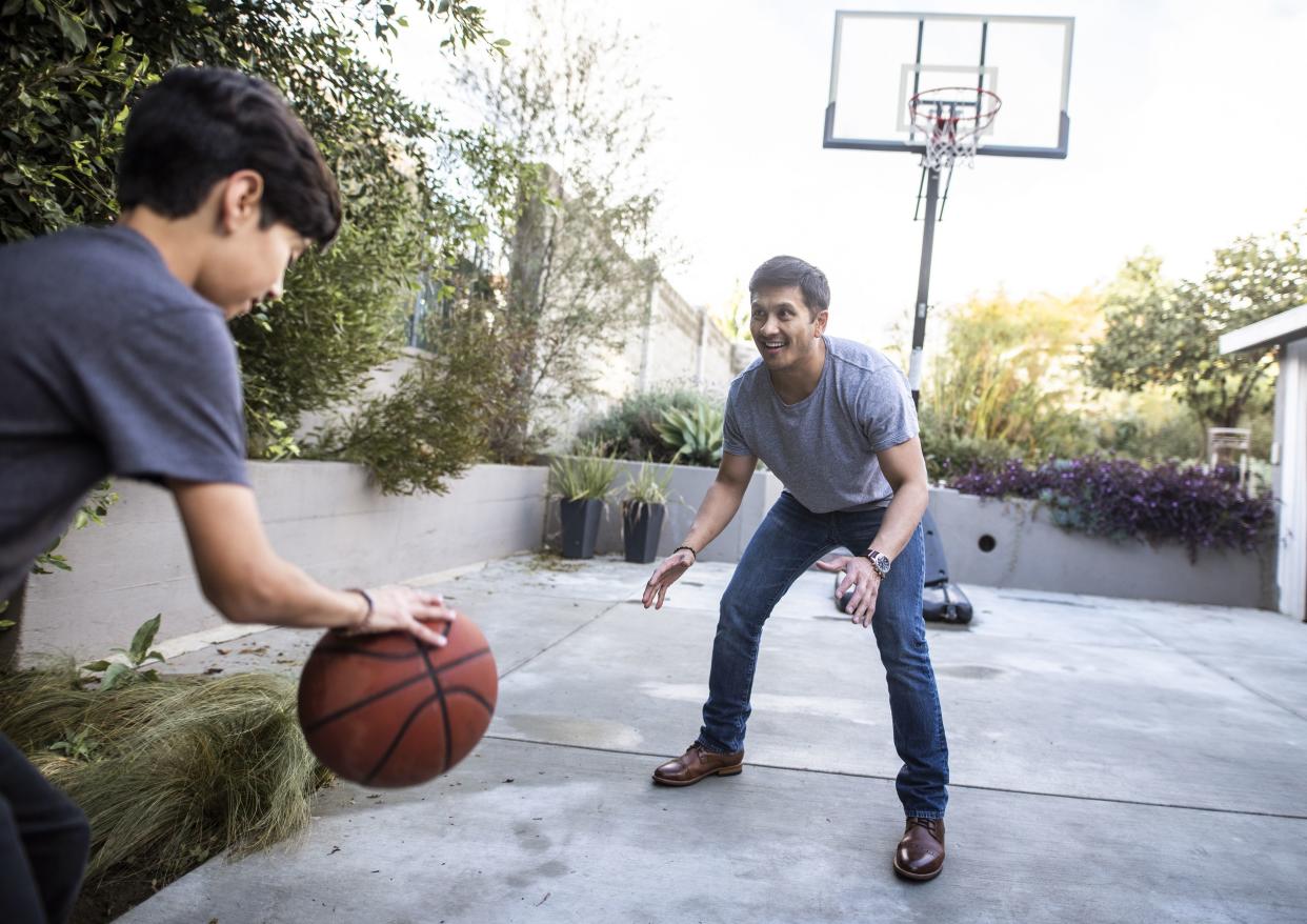 father and son playing basketball on a driveway