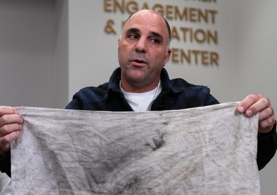 Nir Shani, right, shows the pillowcase he used to cover his mouth to avoid inhaling smoke on the day his kibbutz was attacked by Hamas during a press conference hosted by the Israeli-American Council and Shalom Austin at the Shalom Austin Dell Jewish Community Center, Nov. 16, 2023. Four speakers with family held hostage by Hamas took questions from the local media.
