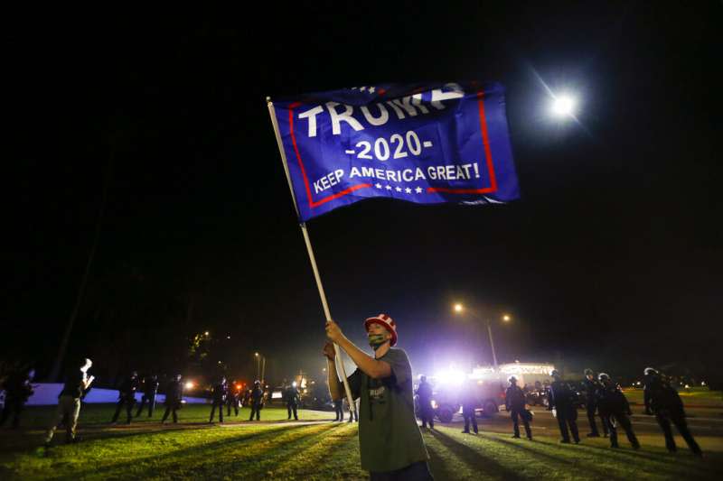 加州一名川普的支持者在比佛利山莊高舉川普的競選旗幟。（美聯社）