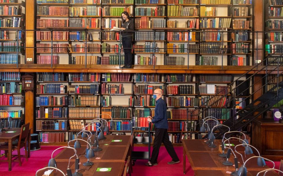 Staff members Saba Chaudry (top) and Michael Booth make final preparations in the reading room at the London Library - Dominic Lipinski/PA Wire