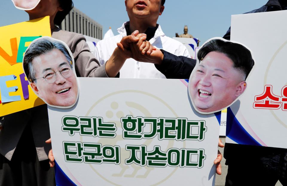 People hold hands behind a sign with cutouts of South Korea's President Moon Jae-in and North Korea's leader Kim Jong Un ahead of the upcoming summit between North and South Korea in Seoul, April 25.