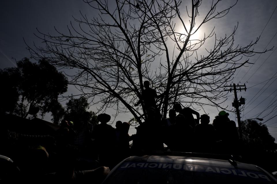 Immigrants, part of the Central American caravan, look at a man that has been detained and placed in a police wagon for, according to the police, smoking marijuana, in Tijuana, Mexico, Wednesday, Nov. 21, 2018. Migrants camped in Tijuana after traveling in a caravan reach the US are weighing their options after a US court blocked President Donald Trump's asylum for illegal border crossers. (AP Photo / Ramon Espinosa)