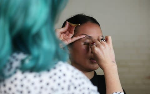 Using a replica of the Ancient Roman copper alloy applicators found at Wroxeter Roman City, in Shropshire, to put on eye make up - Credit: English Heritage