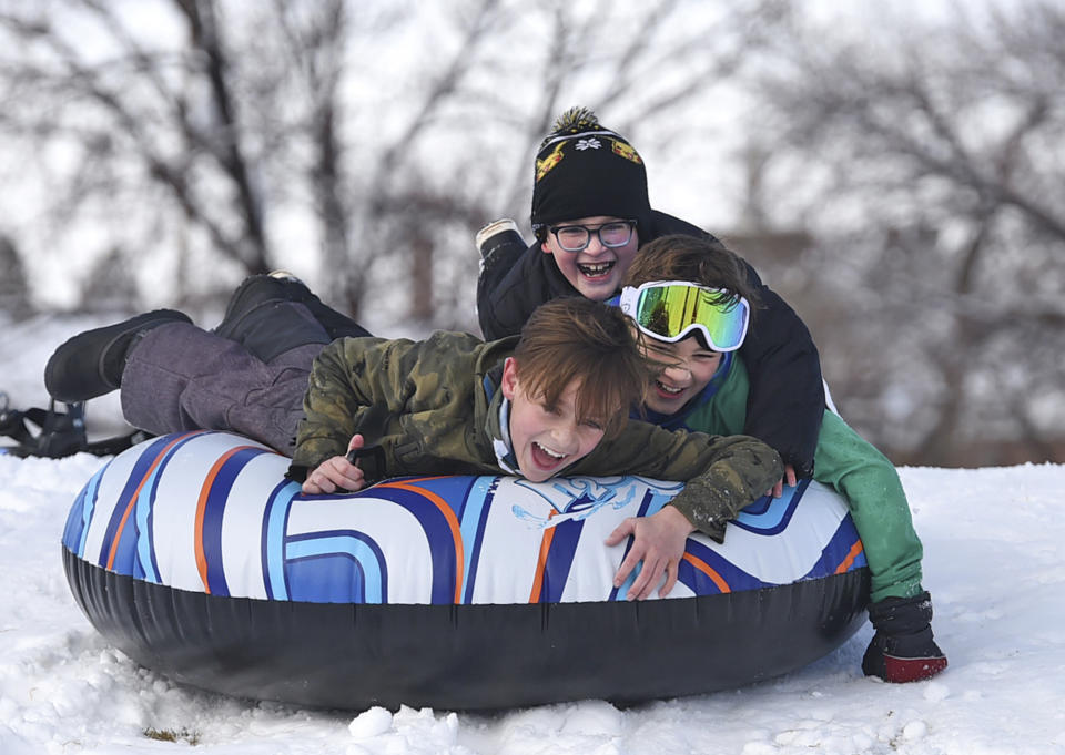 Jacob Clore, 12, front, Lochran Gregory, 12, center, and Ryland Gregory, 9, slide down a hill on the fresh snow that fell overnight at Plumas Street Park in Reno, Nev. on Wednesday, Jan. 27, 2021. A powerful storm packing heavy rain, snow and wind pounded parts of California and western Nevada early Wednesday, toppling trees, and causing power outages and mud flows in vast areas scarred by wildfires. (Andy Barron/Reno Gazette-Journal via AP)