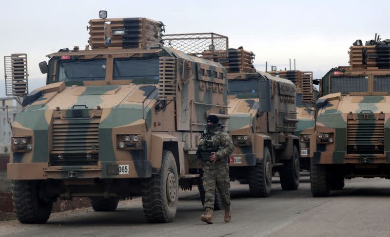 A Turkish soldier walks near Turkish military vehicles in Hazano near Idlib