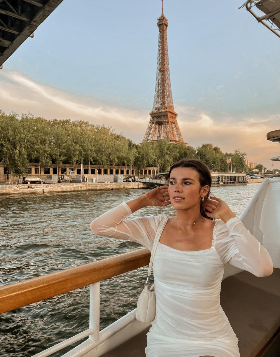 A woman on a boat posing in front of the Eiffel Tower.