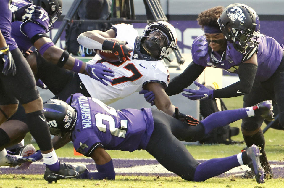 FILE - In this Dec. 5, 2020, file photo, Oklahoma State running back Dezmon Jackson (27) is stopped short of the goal line by TCU defenders Ar'Darius Washington (24) and Dee Winters (13) during the first half of an NCAA college football game in Fort Worth, Texas. Although Oklahoma State will be without All-American running back Chuba Hubbard, who opted out the remainder of the season earlier this month, they have several options to fill the void against Miami in the Cheez-It Bowl. Jackson, a senior, will likely start. (AP Photo/Ron Jenkins, File)