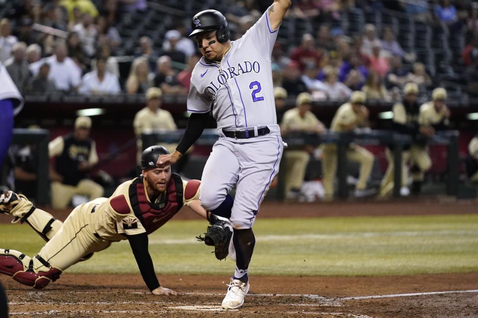 Colorado Rockies' Yonathan Daza (2) scores a run as Arizona Diamondbacks catcher Carson Kelly, left, applies a late tag during the sixth inning of a baseball game Friday, Aug. 5, 2022, in Phoenix. (AP Photo/Ross D. Franklin)