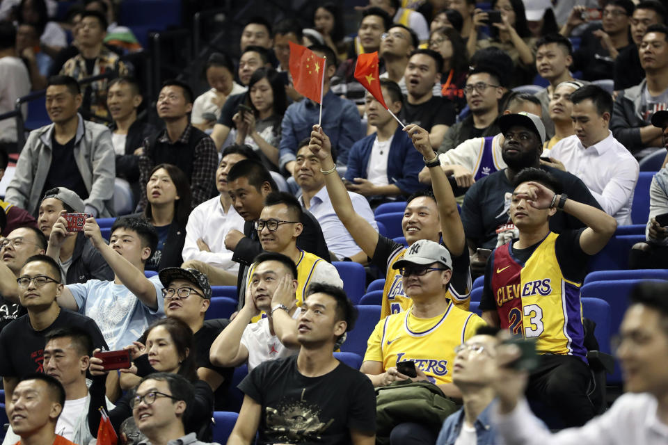 A Chinese fan holds Chinese national flags as he cheers with other fans during a preseason NBA basketball game between the Brooklyn Nets and Los Angeles Lakers at the Mercedes Benz Arena in Shanghai, China, Thursday, Oct. 10, 2019. (AP Photo)