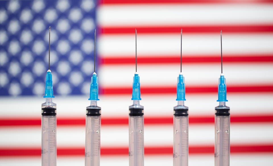 Syringes are seen in front of a displayed U.S. flag in this illustration taken November 10, 2020. REUTERS/Dado Ruvic/Illustration