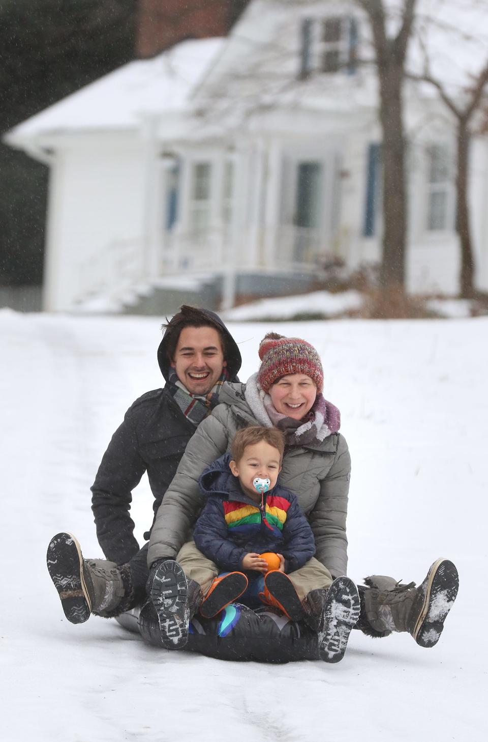 Adam Cartagena, Selena Huber and 2-year-old Cassius Cartagena sled down West 12th Avenue in Gastonia as they enjoy the snow Sunday morning, Jan. 16, 2022.