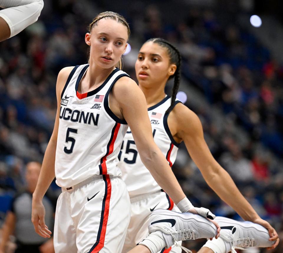 Azzi Fudd (right) and Paige Bueckers stretch in sync.