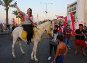 A demonstrator takes a picture with her mobile phone as she sits on a horse during an anti-government protest in the southern city of Tyre