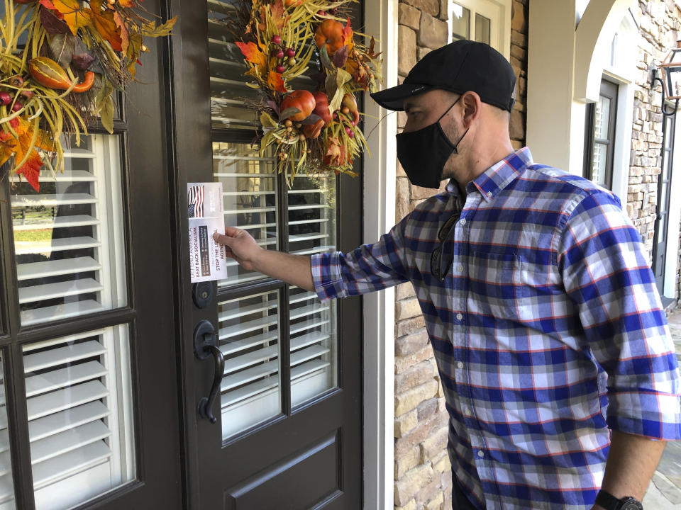 Garrett Bess, vice president of government relations and communications for the conservative activist group Heritage Action For America, leaves information at a residence in a subdivision in Milton, Ga., Friday, Nov. 20, 2020. Bess and a colleague were going door-to-door to encourage people to vote for the conservative candidates in Georgia’s Jan. 5 runoff elections for U.S. Senate. The two Georgia races will decide which party controls the Senate, and that has infused voter turnout efforts by the parties and outside groups with new urgency. (AP Photo/Sudhin Thanawala)