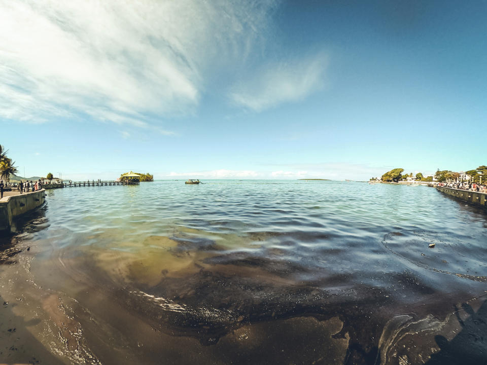 In this photo provided by Grégoire Rouxel fuel is in the ocean leaking from a ship, rear right, that ran aground, Friday, Aug. 7, 2020, in Mauritius. The Indian Ocean island of Mauritius has declared a "state of environmental emergency" after a Japanese-owned ship that ran aground offshore days ago began spilling tons of fuel. Prime Minister Pravind Jugnauth announced the development late Friday, Aug. 7, 2020, as satellite images showed a dark slick spreading near environmental areas the government called "very sensitive." (@gregrouxel via AP)