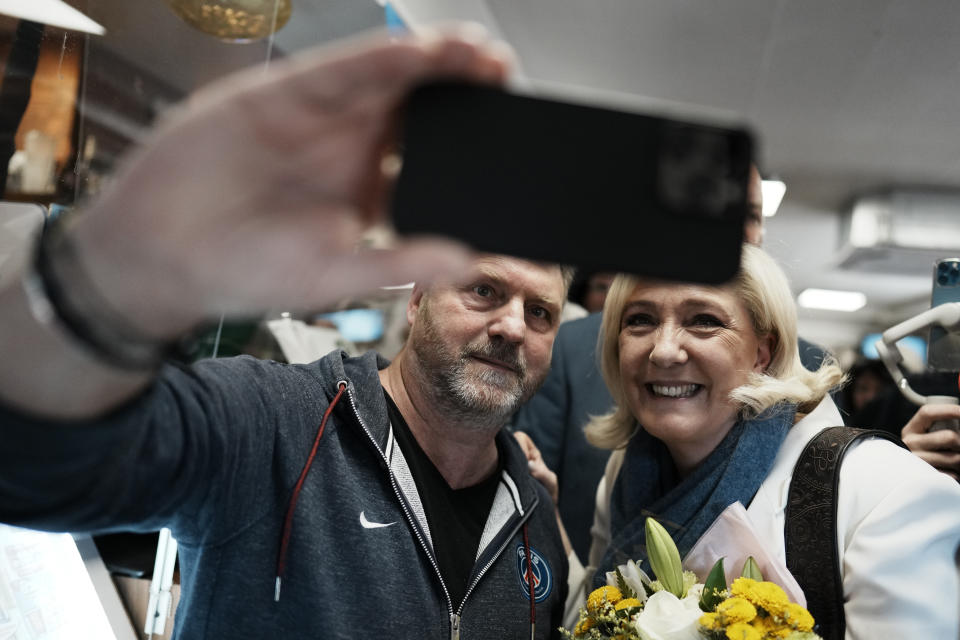 French far-right leader Marine Le Pen, right, poses for a selfie as she campaigns in a cafe in Saint-Remy-sur-Avre, western France, Saturday, April 16, 2022. Marine Le Pen is trying to unseat centrist President Emmanuel Macron, who has a slim lead in polls ahead of France's April 24 presidential runoff election. (AP Photo/Thibault Camus)