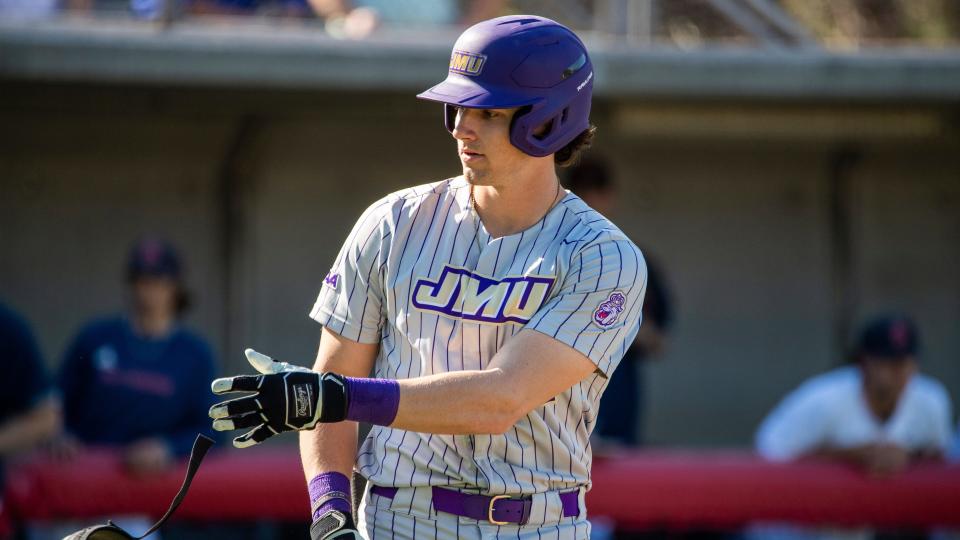 James Madison outfielder Chase DeLauter (22) takes off his gear as he heads to first base after being walked during a game April 2, 2022, in Richmond, Va.