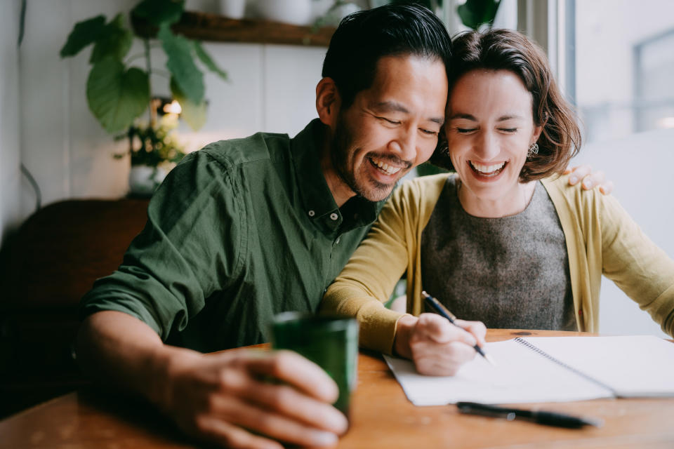 a couple looking at a notebook and laughing