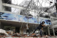 In this Monday, Aug. 6, 2018, file photo, workers remove the debris at a building damaged by an earthquake in Bali, Indonesia. A powerful earthquake struck the Indonesian tourist island of Lombok on Sunday, shaking neighboring Bali, one week after another quake on Lombok killed more than a dozen. (AP Photo/Firdia Lisnawati, File)