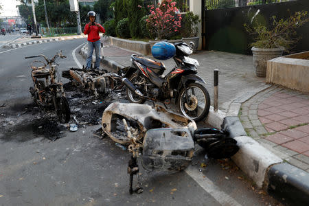 A man takes pictures of damaged motorbikes burned after a riot following the announcement of presidential election results in Jakarta, Indonesia, May 23, 2019. REUTERS/Willy Kurniawan