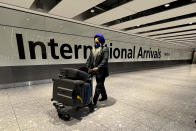 A passenger arrives at London's Heathrow Airport, Monday, Nov. 29, 2021. The new potentially more contagious omicron variant of the coronavirus popped up in more European countries on Saturday, just days after being identified in South Africa, leaving governments around the world scrambling to stop the spread. In Britain, Prime Minister Boris Johnson said mask-wearing in shops and on public transport will be required, starting Tuesday. (AP Photo/Frank Augstein)