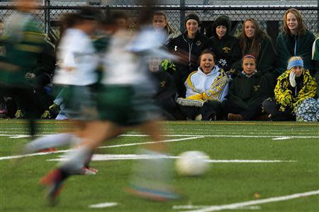 Fifteen year-old Sarah Steenhuysen (C seated) cheers on her high school soccer teammates from the sidelines during a game against Bishop Feehan in Attleboro, Massachusetts October 25, 2013. REUTERS/Brian Snyder