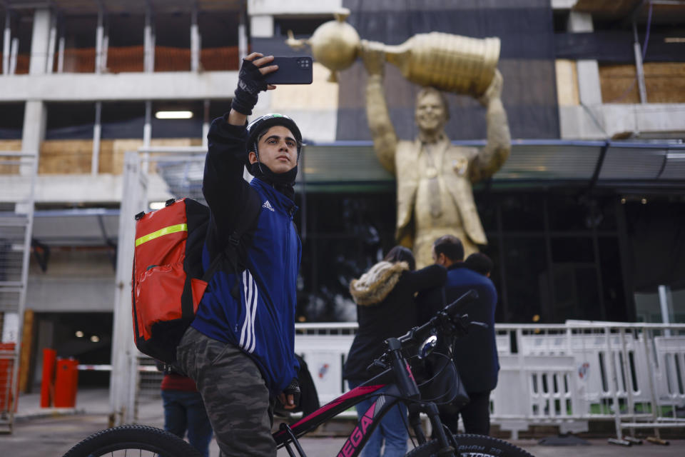 Un ciclista se saca una selfie frente a la estatua de Marcelo Gallardo, ex técnico de River Plate, afuera del estadio Monumental en Buenos Aires, el martes 30 de mayo de 2023. (AP Foto/Iván Fernández)