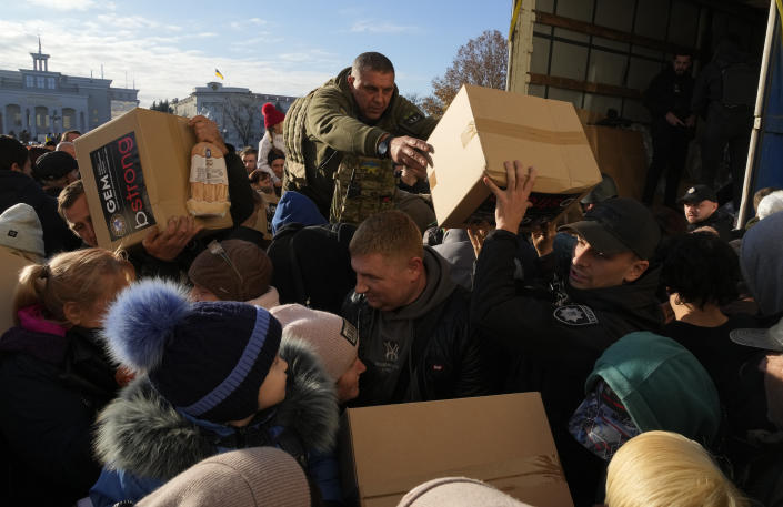 People receive humanitarian aid on central square in Kherson, Ukraine, Tuesday, Nov. 15, 2022. Waves of Russian airstrikes rocked Ukraine on Tuesday, with authorities immediately announcing emergency blackouts after attacks from east to west on energy and other facilities knocked out power and, in the capital, struck residential buildings. (AP Photo/Efrem Lukatsky)
