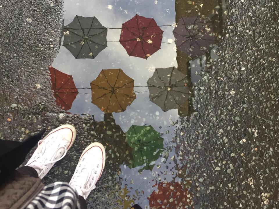 reflection of the umbrella street art in a puddle on the streets of dublin ireland