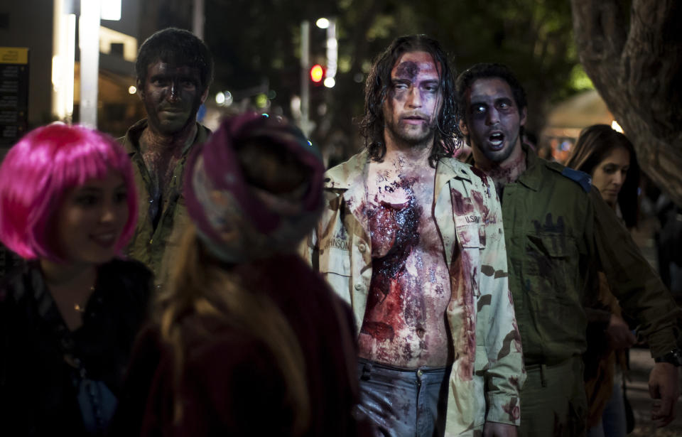 Israelis dressed as a zombies takes part in the customary 'Zombie Walk' in the city of Tel Aviv, on the eve of the Jewish holiday of Purim, late on March 15, 2014. The carnival-like Purim holiday is celebrated with parades and costume parties to commemorate the deliverance of the Jewish people from a plot to exterminate them in the ancient Persian empire 2,500 years ago, as described in the Book of Esther. AFP PHOTO/DAVID BUIMOVITCH        (Photo credit should read DAVID BUIMOVITCH/AFP/Getty Images)